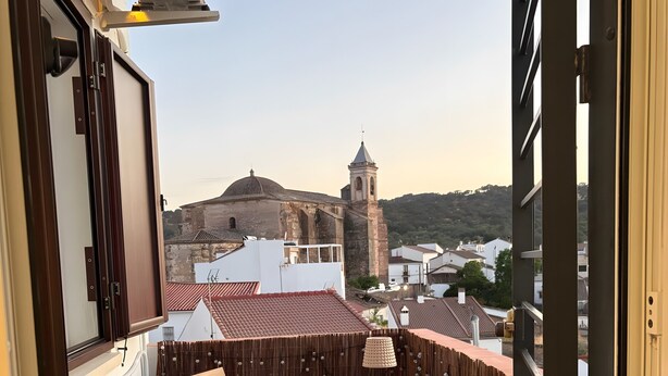 A balcony with a table and chairs, a view of a historic building, and a tiled floor.