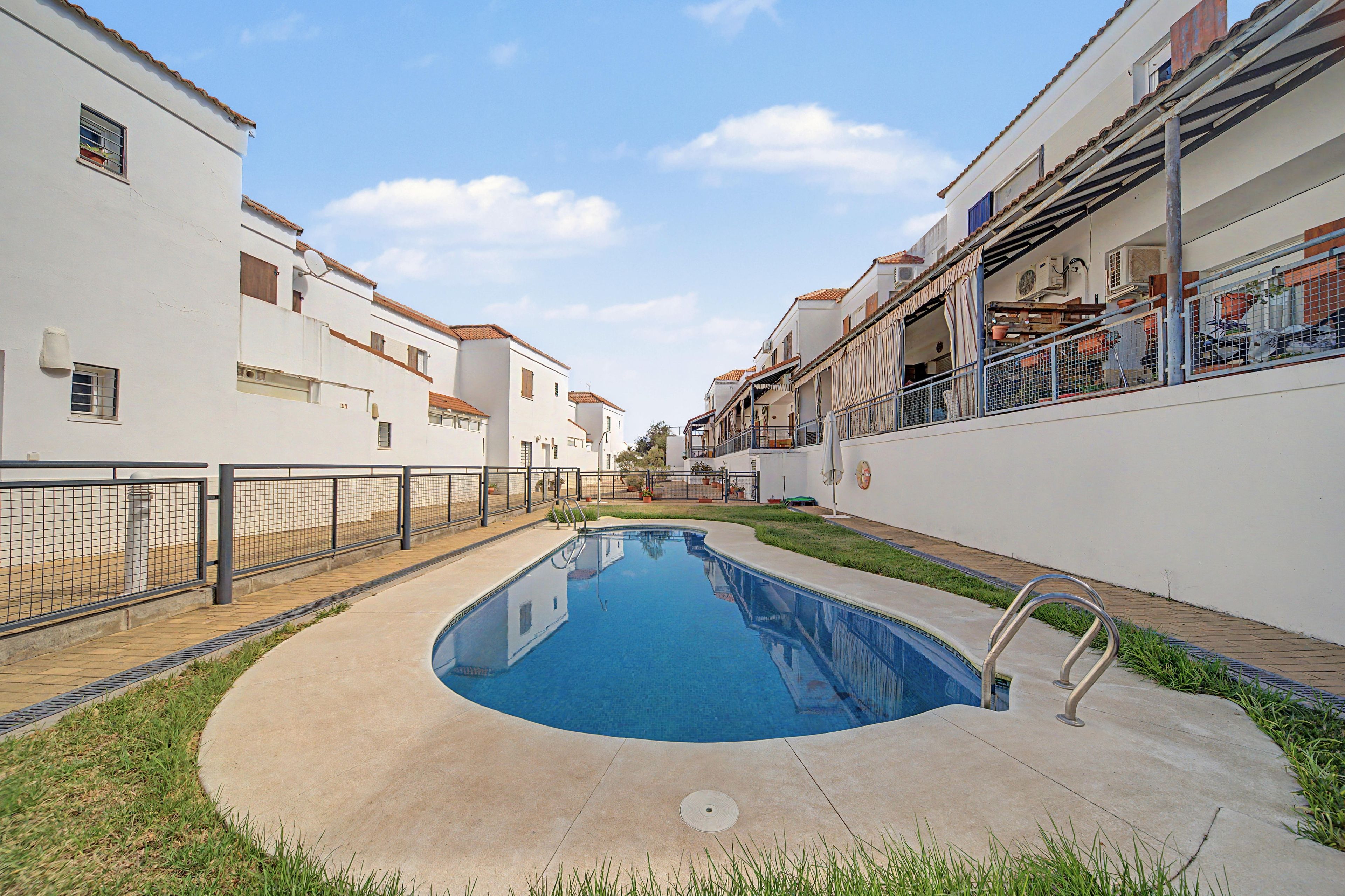 Una piscina rodeada por una cerca baja, con un cielo despejado arriba.