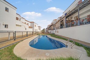 A swimming pool surrounded by a low fence, with a clear sky above.