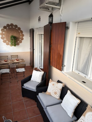 Une pièce comprenant un coin repas, un ensemble de canapés, un élément décoratif mural et une fenêtre avec des rideaux.