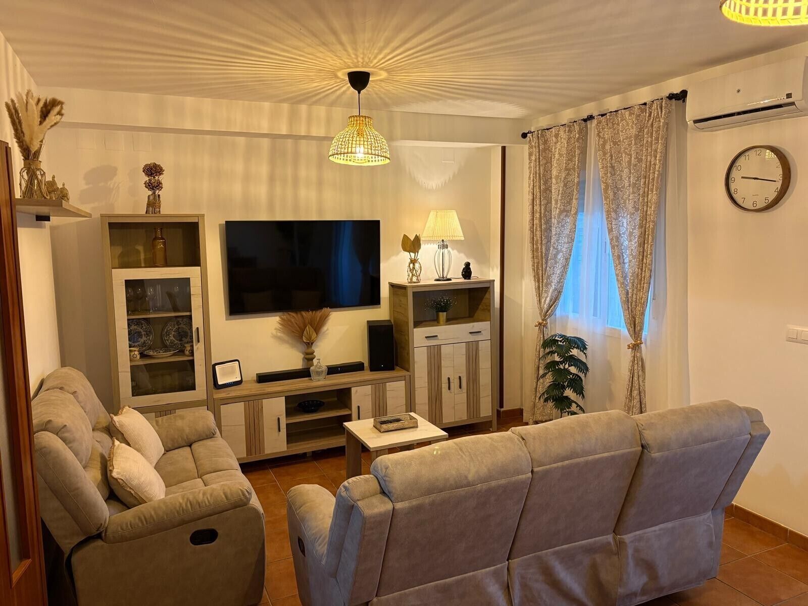 Een woonkamer met een bank, televisie, kast en decoratieve objecten.