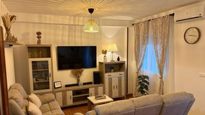A living room with a sofa, TV, cabinet, and decorative items.