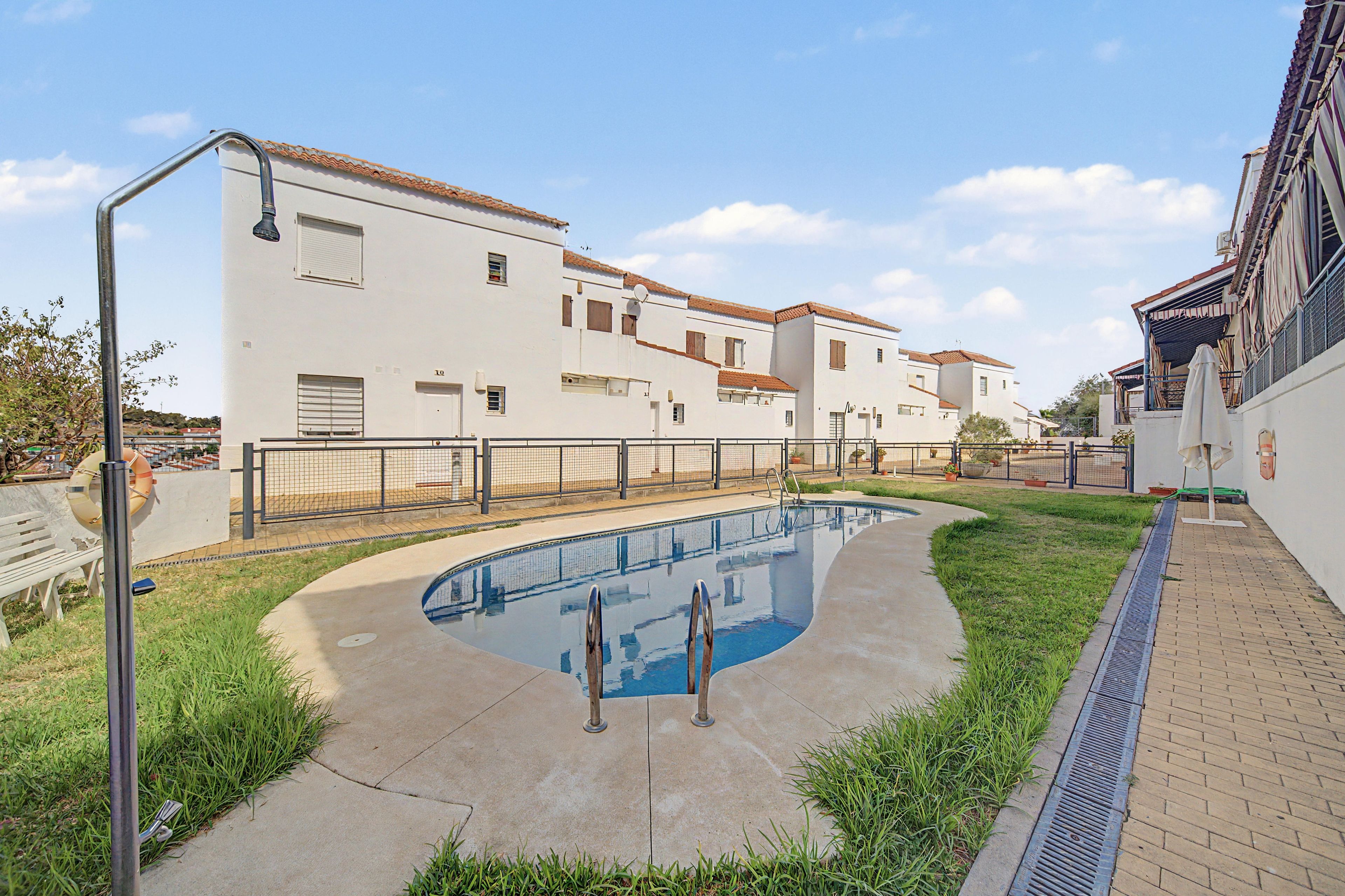 Una piscina con borde curvo, rodeada de un sendero empedrado y un área con césped.