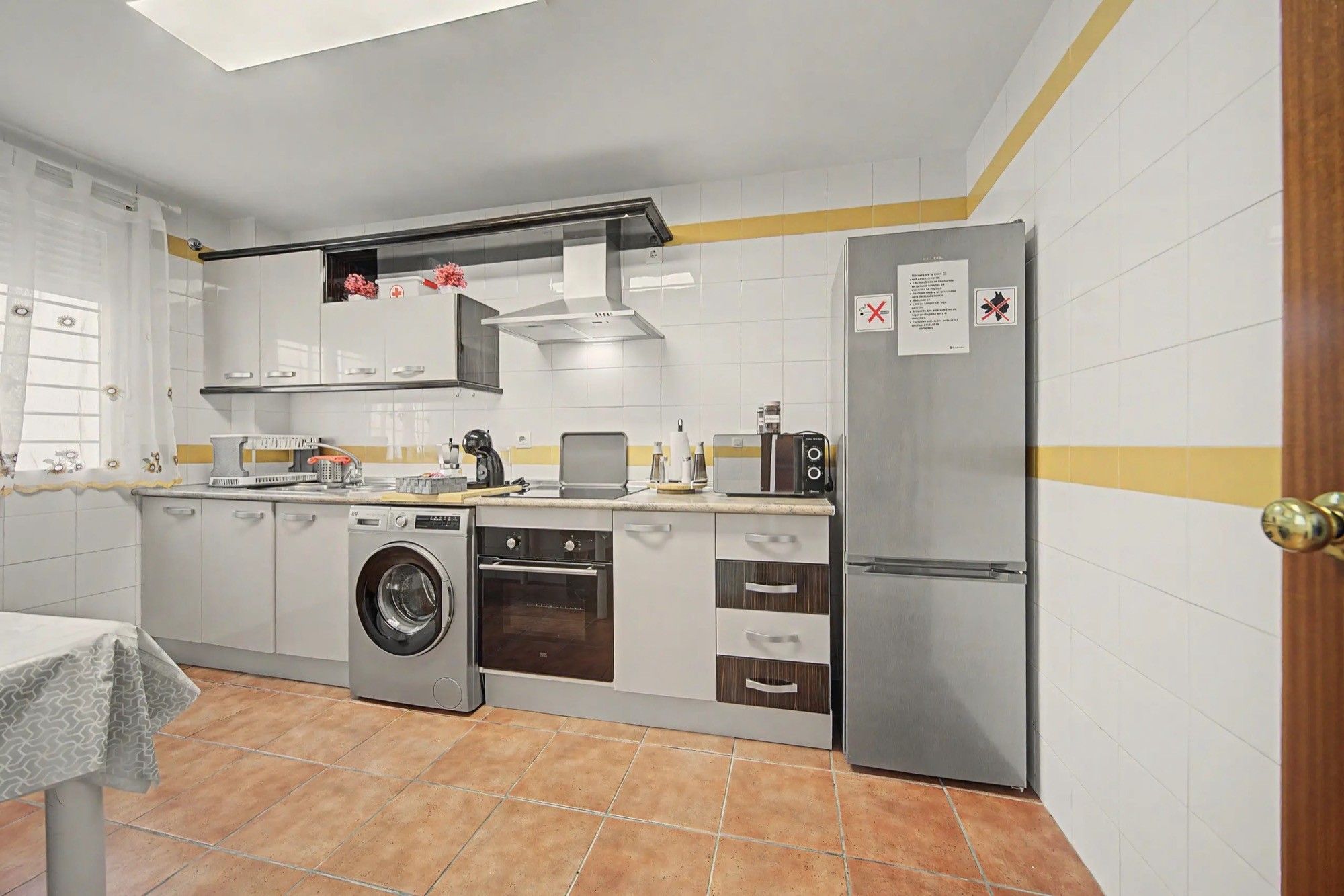 A compact kitchen with a washing machine, oven, and a refrigerator.
