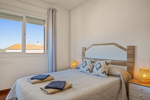 Un dormitorio con cama, dos lámparas de noche, una ventana con cortinas y vistas al exterior.