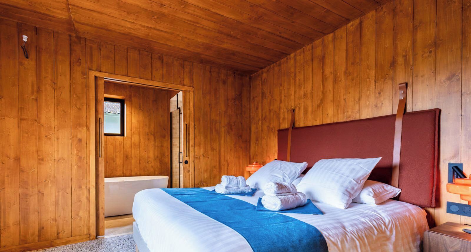 Ein Zimmer mit Holzwänden, einem Bett, einem Fenster und einer Tür.