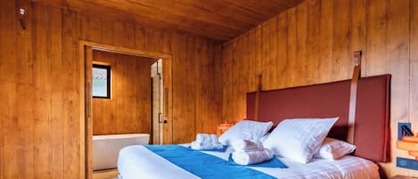 Ein Zimmer mit Holzwänden, einem Bett, einem Fenster und einer Tür.