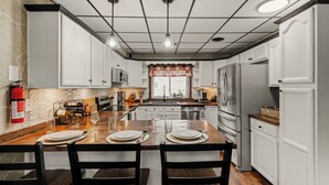 A modern kitchen with white cabinets, a wooden island, stainless steel appliances, and a fire extinguisher. - Lantz Retreat  Hot Tub • Spacious Deck (Lebanon)