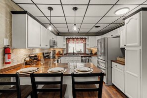 Een moderne keuken met witte kasten, een houten eiland, roestvrijstalen apparatuur en een brandblusser.