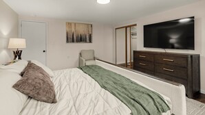 A bedroom with a bed, a dresser, a television, and a painting on the wall. - Lantz Retreat  Hot Tub • Spacious Deck (Lebanon)