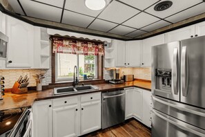 A modern kitchen with white cabinetry, stainless steel appliances, and a wooden countertop. - Lantz Retreat  Hot Tub • Spacious Deck (Lebanon)