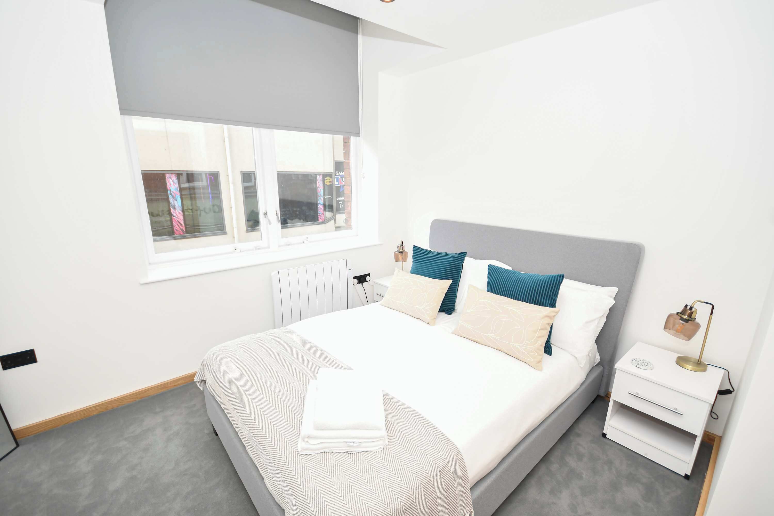 Un dormitorio moderno con una cama grande, una mesita de noche y un radiador.