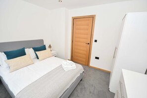 Quarto com cama, mesa de cabeceira e guarda-roupa.