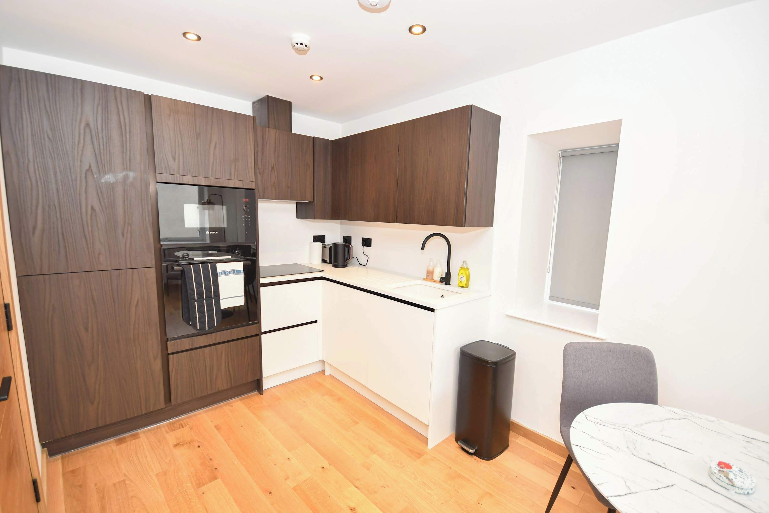 A compact kitchen with a built-in oven, a sink, and a window.