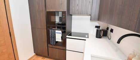 A compact kitchen with a built-in oven, a microwave, and a stovetop.