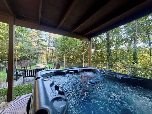Een hottub onder een houten pergola met uitzicht op bebossing.