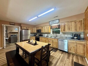 A kitchen with wooden cabinets, a stainless steel refrigerator, a microwave, a dishwasher, and a dining table with chairs. - Cozy Bear Chalet/Hot tub/Fire Pit/Dollywood (Sevierville)