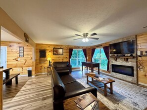 A cozy cabin interior with a leather sofa, a wooden coffee table, a fireplace, and a television. - Cozy Bear Chalet/Hot tub/Fire Pit/Dollywood (Sevierville)