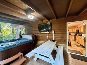 Ein Whirlpoolbereich mit Holzterrasse, einer Bank und einem an der Wand befestigten Fernseher.