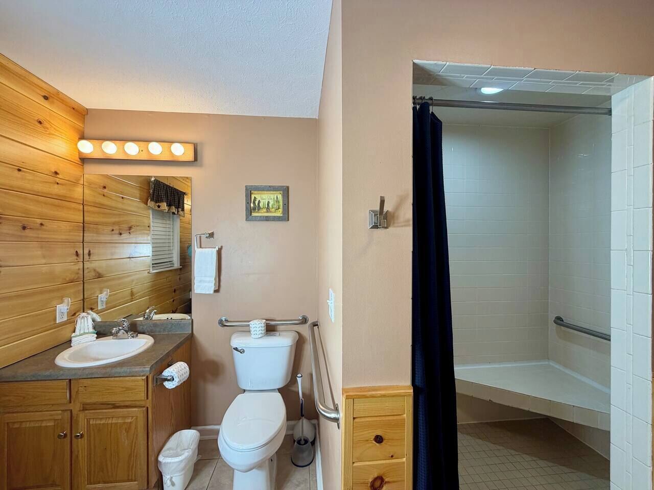 Une salle de bain avec un meuble-lavabo en bois, des toilettes, un lavabo et un espace douche.