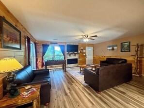 Un interior de cabaña acogedor con un sofá, un sillón y una chimenea.