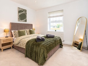 A bedroom with a bed, bedside tables, a window, and a mirror.