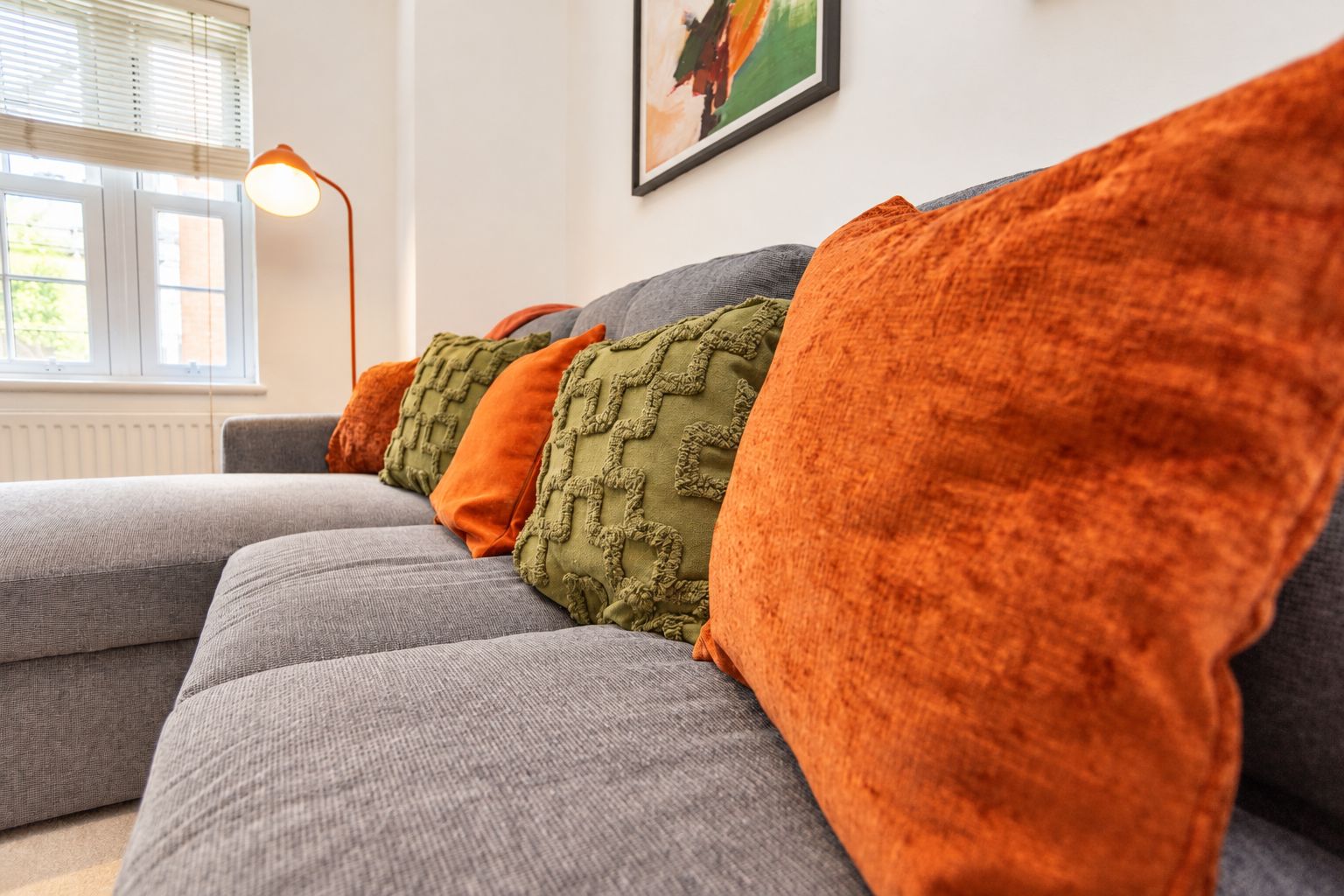 A grey sofa with multiple cushions in various textures and colors.