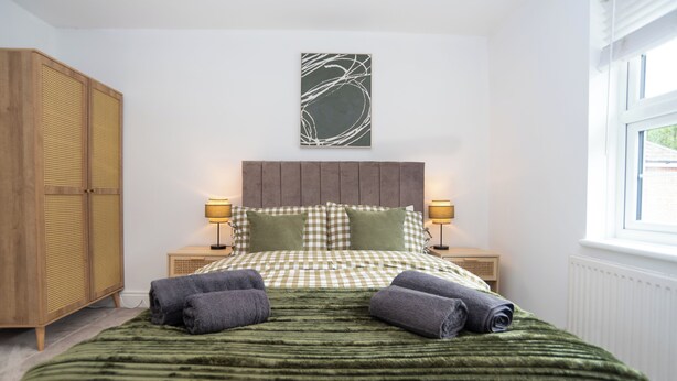 Un dormitorio con una cama, dos mesitas de noche, un armario y una ventana.
