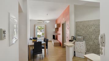 A modern kitchen with a built-in oven, a dining area with a table and chairs, and a view of the outside through a window.