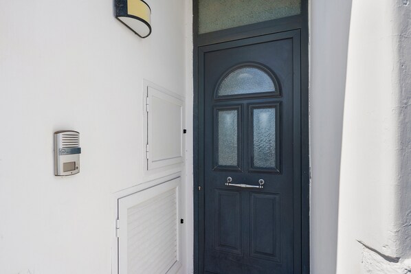 Una porta nera con un pannello in vetro e una maniglia, una parete bianca con un lampadario e un basculante da garage bianco.