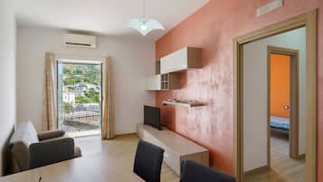 A modern living space with a dining area, a TV, and a view of a residential area.