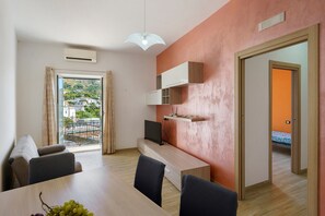 Un soggiorno moderno con zona pranzo, televisore e vista su un quartiere residenziale.