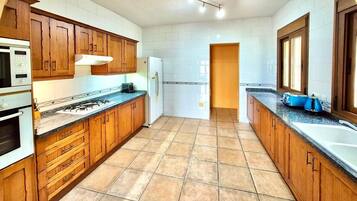 A kitchen with wooden cabinets, a gas stove, a refrigerator, and a sink.