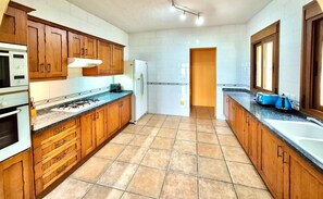 A kitchen with wooden cabinets, a gas stove, a refrigerator, and a sink.