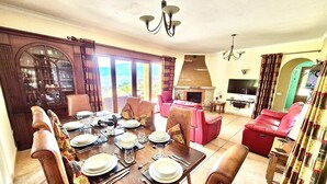 A dining area with a wooden table set for a meal, surrounded by chairs.