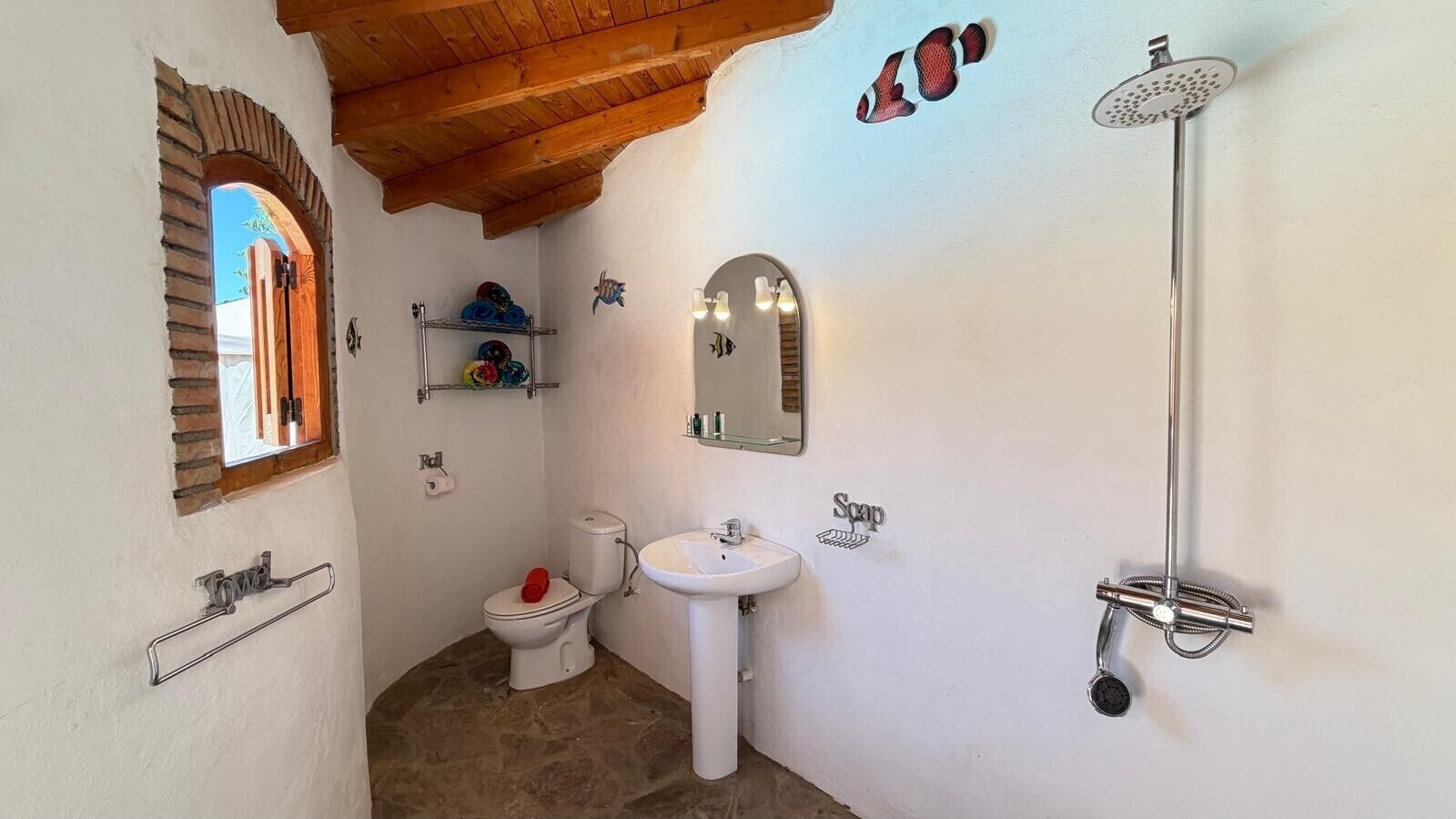 A bathroom with a white sink, a toilet, a shower, and a towel rack.