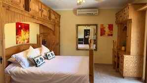 A bedroom with a bed, wooden wardrobe, and a mirror.