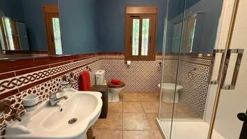 A bathroom with a sink, two toilets, a shower, and patterned tiles.
