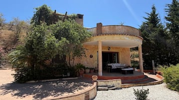 Un edificio circular con un patio cubierto, asientos al aire libre y un jardín con diversas plantas.