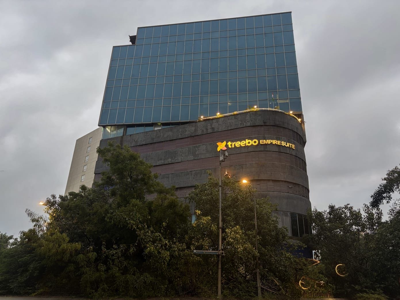 A modern building with a glass facade and a sign for 'Treebo Empire Suite.'