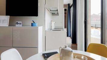 Ein Hotelzimmer mit Esstisch, Wasserkocher und Smartphone.