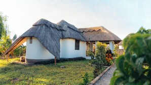 Ein traditionelles Reetdachhaus mit weißer Fassade, umgeben von einem gepflegten Garten mit verschiedenen Pflanzen und einem Kiesweg.