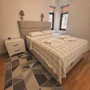 Une chambre à coucher avec un lit, des tables de chevet, un tapis à motifs et une fenêtre avec des stores.