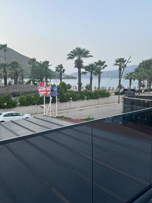 A hotel with a view of the sea, palm trees, and flags. - Beach Suite XL İcmeler (Muğla)