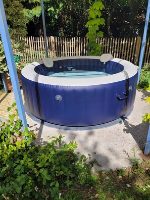 A hot tub in a garden with a wooden fence in the background. - Gîte Aire Holiday Home with Shared Pool, Communal Terrace, and Wi-Fi (Juvigny Val d'Andaine)