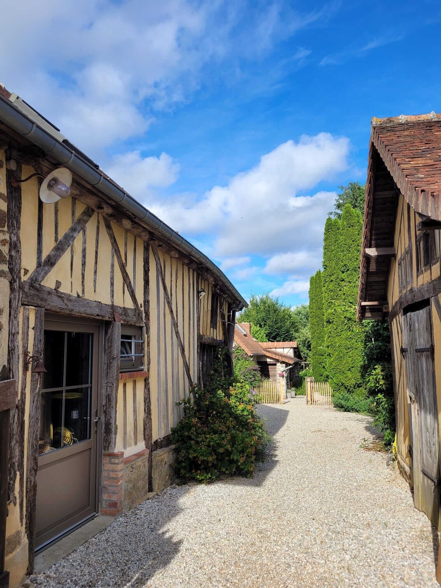 A traditional half-timbered building with a gravel path leading to a wooden gate.