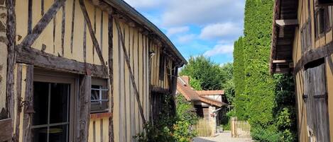 A traditional half-timbered building with a gravel path leading to a wooden gate.