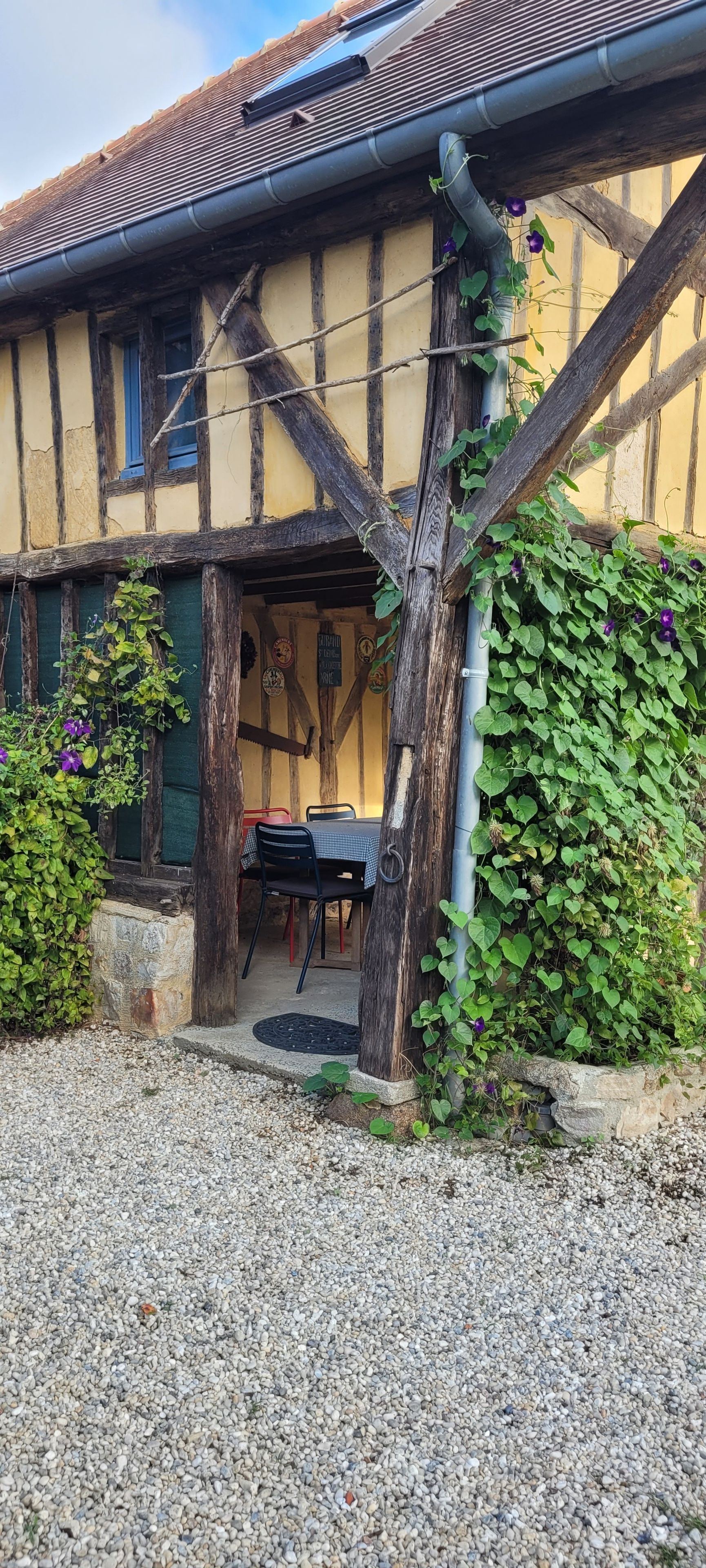 A traditional half-timbered building with a gravel driveway and a table and chairs outside.