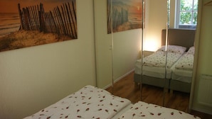 Quarto com cama, janela e pintura na parede.