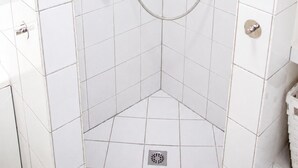 Box de chuveiro no canto, com chuveiro manual e fixo, e paredes revestidas de azulejos brancos.